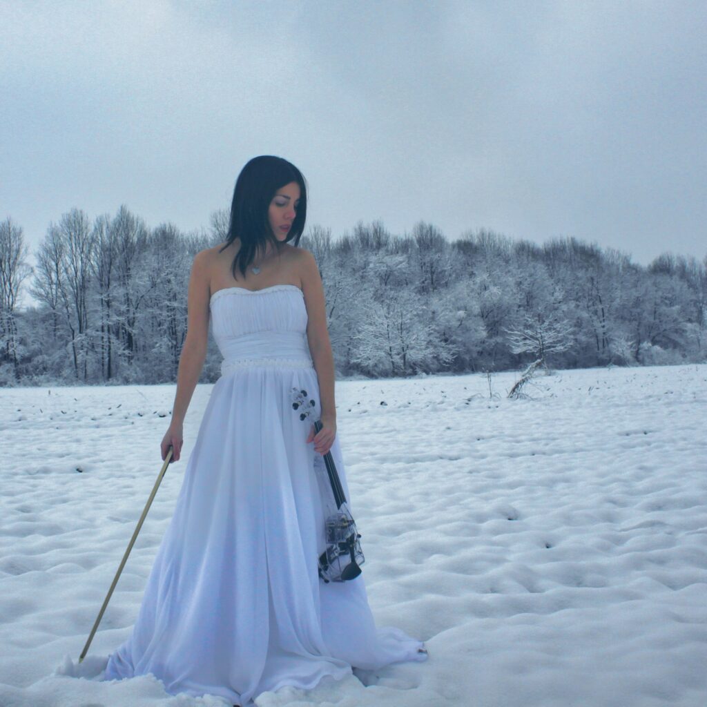 VioDance violinist in the snow with a transparent violin and white dress